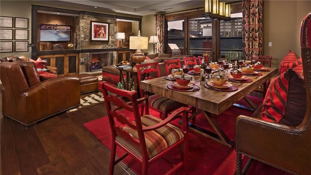 A dining area with a wooden table set for a meal, surrounded by red upholstered chairs.