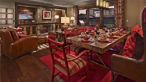 A dining area with a wooden table set for a meal, surrounded by red upholstered chairs. - Grouse Mountain 510 4 BedroomCondo By Moving Mountains (Steamboat Springs)