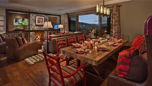 Un coin repas avec une table en bois dressée pour le repas, entourée de chaises à revêtement rouge.