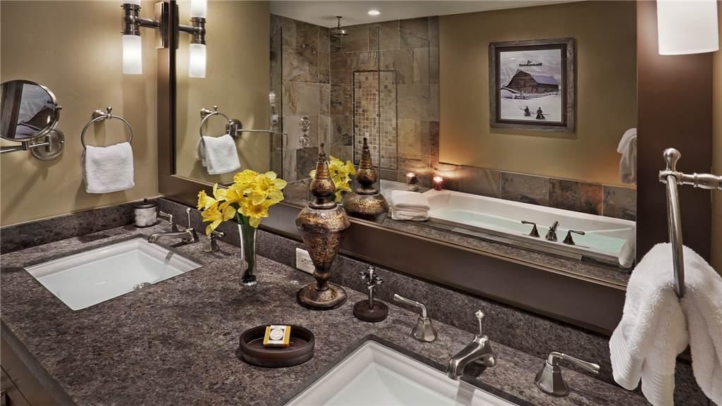 Un bagno moderno con due lavabi, uno specchio grande e una vasca da bagno.