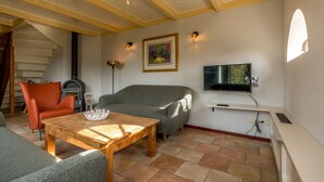 Uma sala de estar com sofá, poltrona, mesa de madeira e lareira.