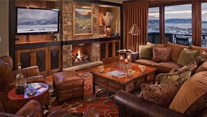 Una sala de estar acogedora con chimenea, muebles de cuero, un televisor de pantalla plana y vistas panorámicas.
