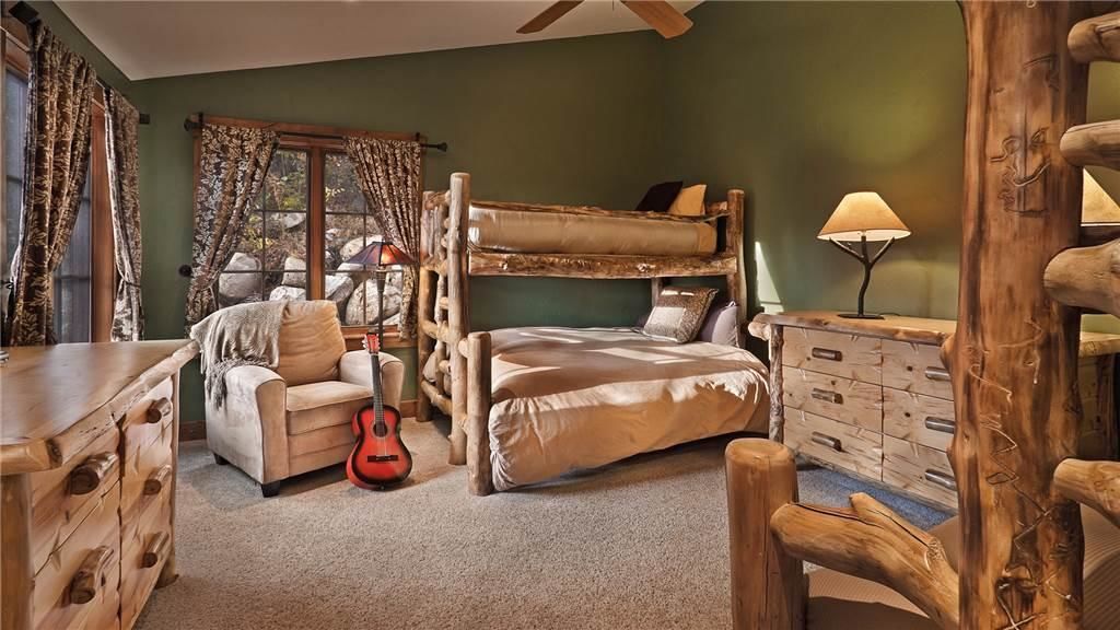 A rustic room with a bunk bed, a wooden dresser, a chair, and a guitar.