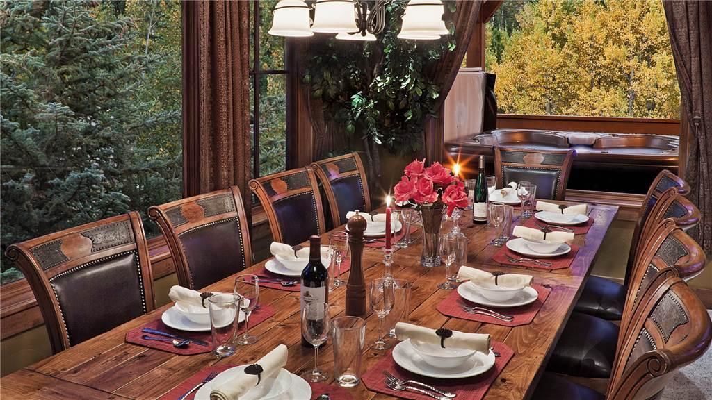 A dining room with a wooden table set for six, surrounded by leather chairs.