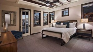Ein Schlafzimmer mit einem großen Bett, einem Schreibtisch, einem Stuhl und einem Fenster mit Blick auf die Berge.