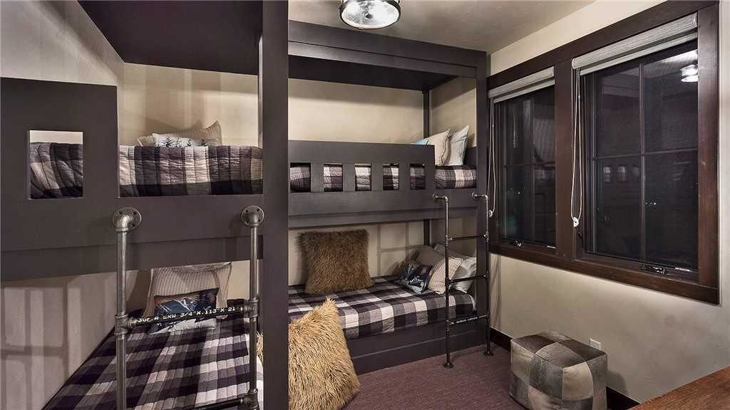 Une chambre avec un lit superposé, une fenêtre, un miroir et un petit tabouret.