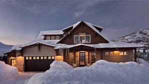 Ein zweistöckiges Haus mit Garage, Veranda und einem mit Schnee bedeckten Dach.