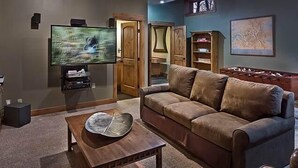 Een woonkamer met een televisie, een bank, een salontafel en een boekenkast.