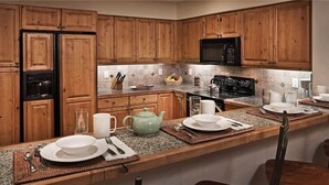 A kitchen with wooden cabinets, a black microwave, a stove, and a granite countertop. - Argentiere 341 3 BedroomCondo By Moving Mountains (Steamboat Springs)