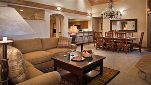 A cozy living room with a sofa, coffee table, and dining area with chairs and a chandelier. - Argentiere 341 3 BedroomCondo By Moving Mountains (Steamboat Springs)