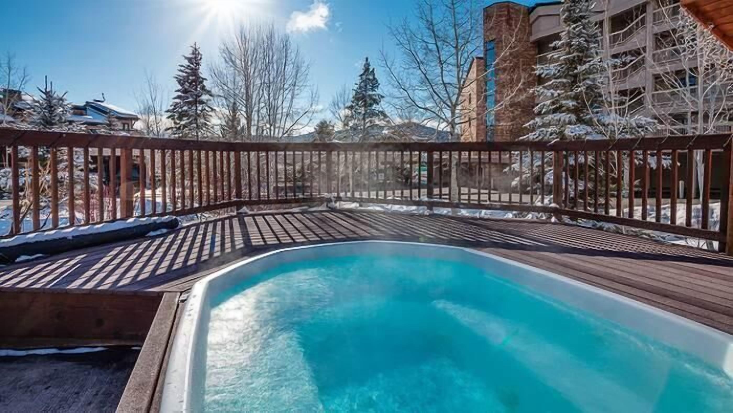 A swimming pool with a wooden deck and a metal fence.