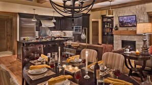 A modern dining area with a central island, dark wood furniture, and a fireplace.