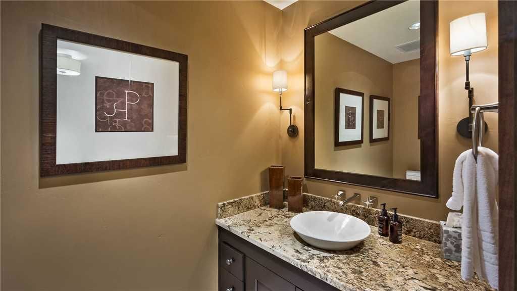 Un baño con un espejo grande, obras de arte enmarcadas, un lavabo y un perchero para toallas.