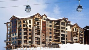 A multi-story hotel with balconies, ski lifts, and a snowy landscape. - Skyfall Ridge 702 2 BedroomCondo By Moving Mountains (Steamboat Springs)