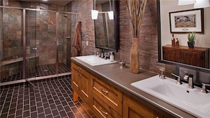 A modern bathroom with a glass shower enclosure, two sinks, wooden vanity, and a large mirror. - Falconhead Lodge North 5 BedroomHoliday home By Moving Mountains (Steamboat Springs)