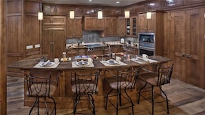 A kitchen with wooden cabinets, a central island with bar stools, and a built-in stove.