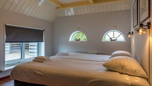 Quarto com duas camas, uma janela grande e um claraboia.