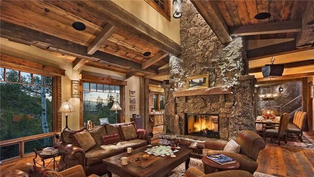 A rustic interior with a stone fireplace, wooden beams, and a cozy seating area with a fireplace. - Gold Mine Lodge 6 BedroomHoliday home By Moving Mountains (Steamboat Springs)