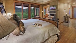 Une chambre avec un grand lit, une cheminée et une vue sur l’extérieur.