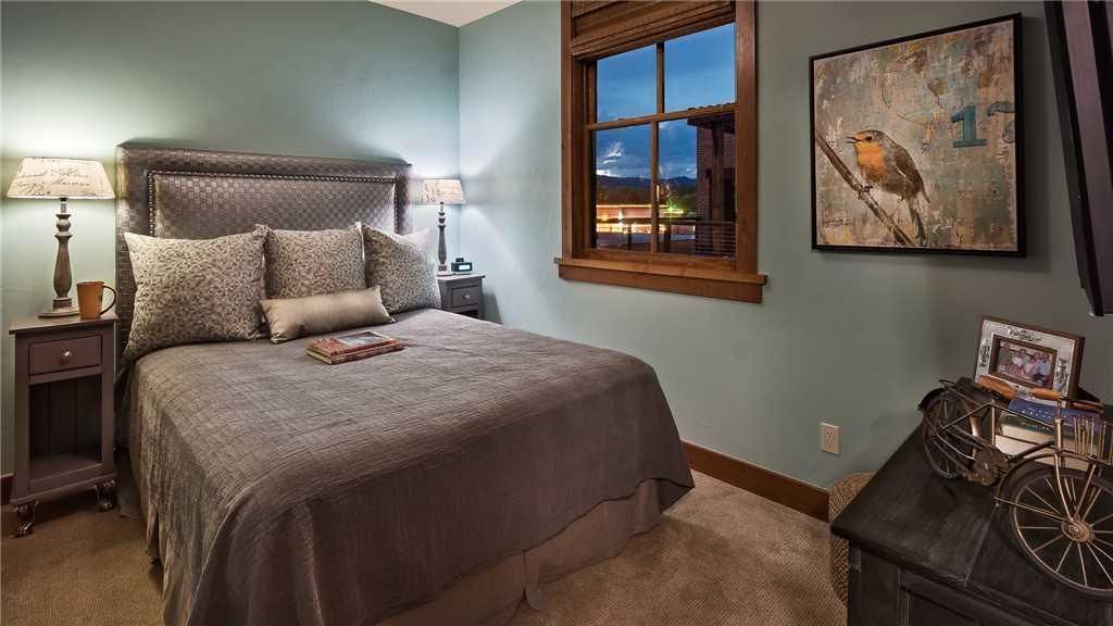 A bedroom with a large bed, bedside tables, a window, and a wall-mounted artwork.