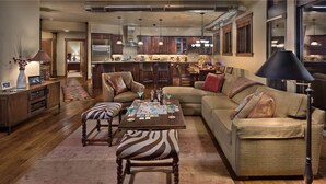 A spacious living room with a large sectional sofa, a wooden coffee table, and a zebra-striped ottoman.