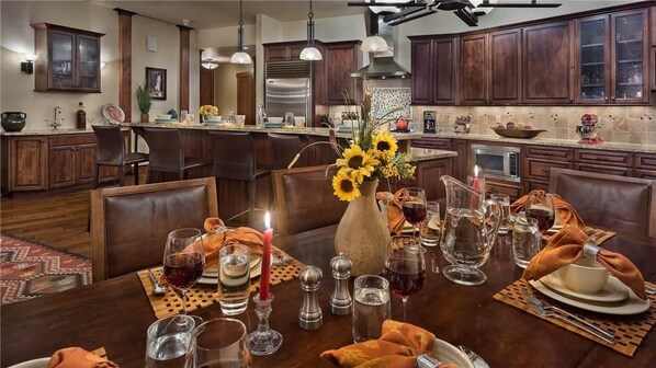 A modern kitchen with dark wood cabinets, stainless steel appliances, and a dining area set for a meal.