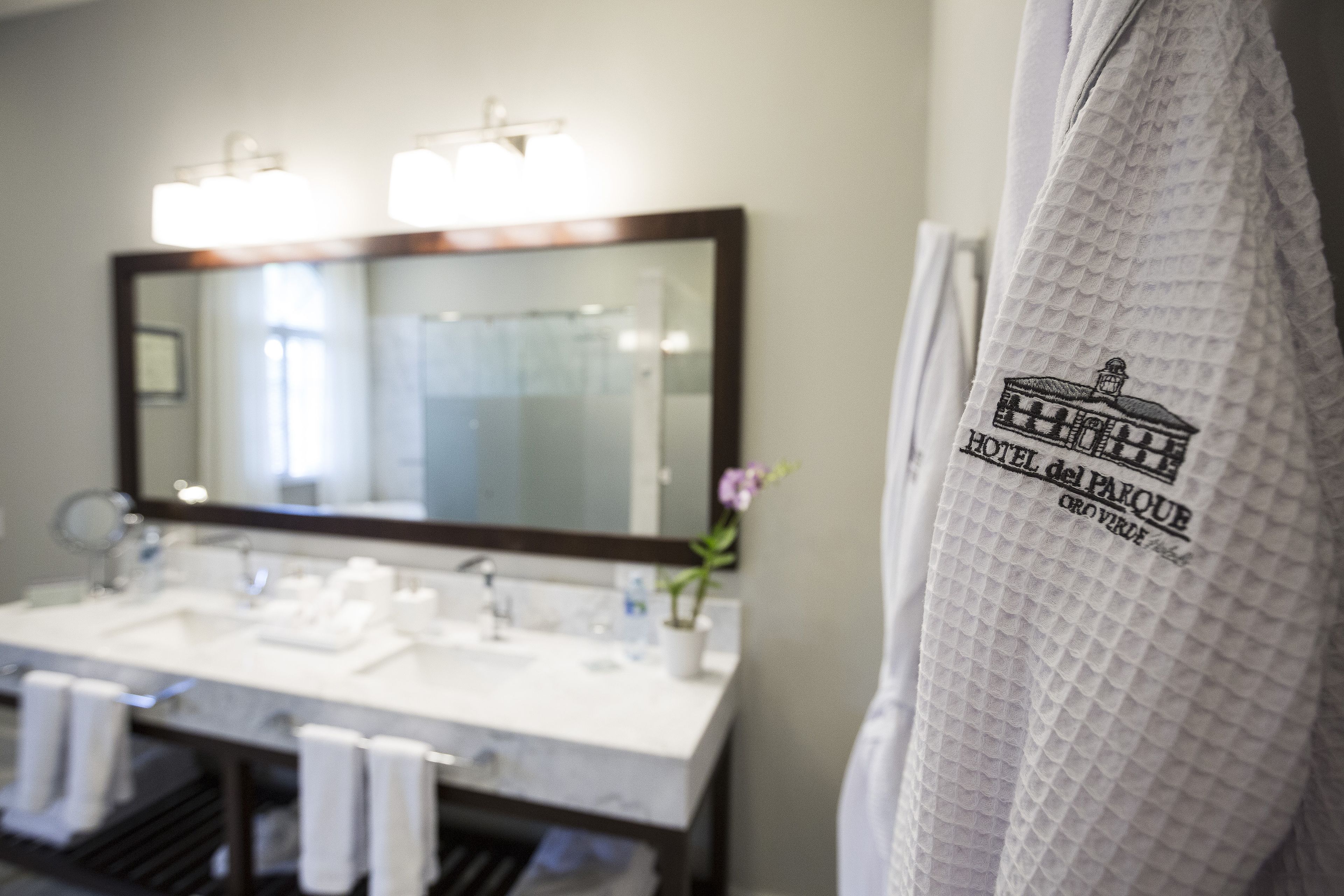 A bathroom with a large mirror, a white sink, and a towel rack.