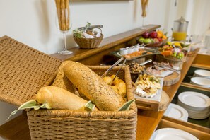 Um buffet de café da manhã com pães, doces, frutas e bebidas.