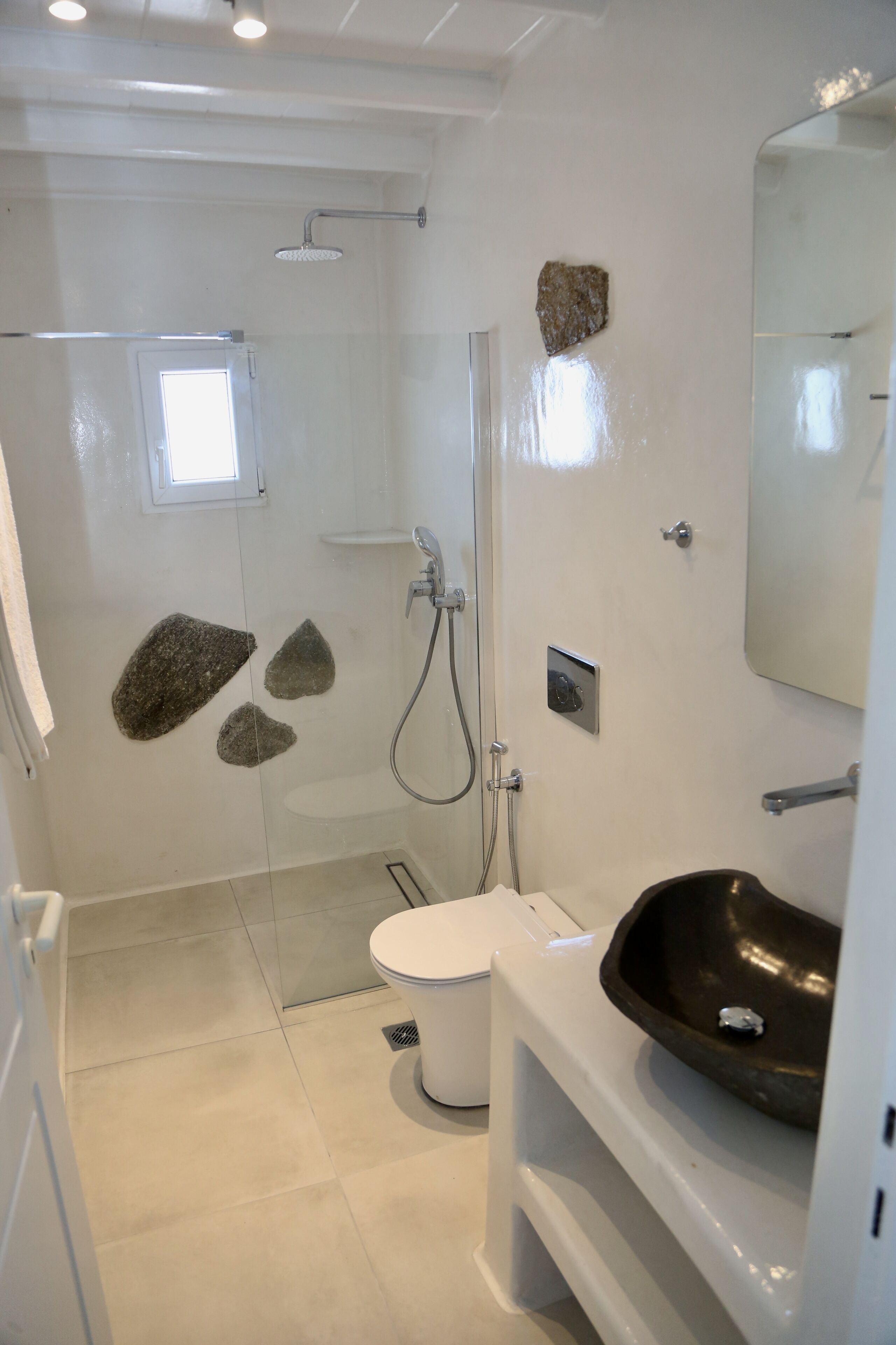 A bathroom with a glass-enclosed shower, a white toilet, and a black sink.