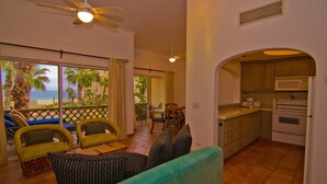 Una sala de estar con vistas a la playa, un comedor y una cocina.