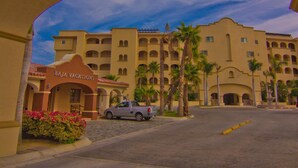 Un arco con el texto "Baja Vacations" y un edificio con varios balcones y palmeras.