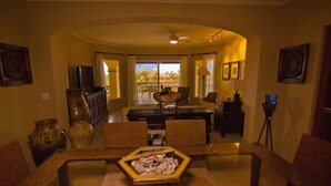 A living room with a television, a dining table, and a view of the outdoors. - Las Mananitas LM F4205 2 Bedroom Condo By Seaside Los Cabos (San José del Cabo)