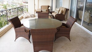 A balcony with wicker furniture, a glass table, and a city view. - Las Mananitas LM 3 Villa 3501 3 Bedroom Villa By Seaside Los Cabos (San José del Cabo)