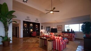 Un salón amplio con techo alto, ventilador de techo, chimenea y un ventanal grande.