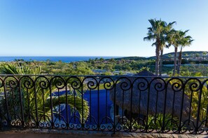A coastal view with a metal fence, palm trees, and a thatched structure. - Casa Vida Home 4 Bedroom Villa By Seaside Los Cabos (San José del Cabo)
