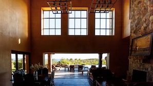 A spacious interior with a high ceiling, large windows, and a view of the outdoors.