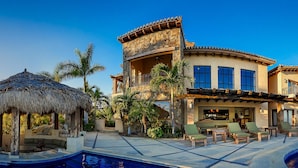 A luxurious resort with a pool, outdoor seating, and a thatched-roof structure.