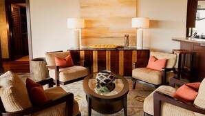 A modern living room with wicker furniture, a central coffee table, and a large abstract painting on the wall. - 115D Waiulu Street Hualalai (Kailua-Kona)