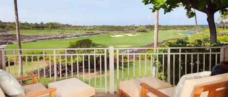 Un balcón con muebles de madera y vistas a un campo de golf.