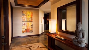 A hallway with a wooden ceiling, a stone statue, and two abstract paintings on the wall. - 115D Waiulu Street Hualalai (Kailua-Kona)