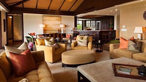 A spacious living area with multiple sofas and armchairs, a round ottoman, and a bar area in the background. - 115D Waiulu Street Hualalai (Kailua-Kona)