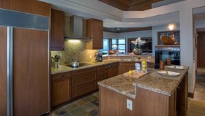 A modern kitchen with wooden cabinets, granite countertops, and a central island. - 120A Waiulu Street Hualalai (Kailua-Kona)