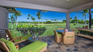 A balcony with wicker furniture, a table, and a view of a golf course. - 104A Waiulu Street Hualalai (Kailua-Kona)
