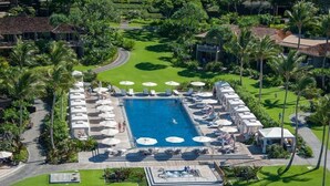 A large rectangular swimming pool surrounded by lounge chairs and umbrellas, with palm trees and a well-maintained lawn. - 104A Waiulu Street Hualalai (Kailua-Kona)