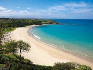 Una playa costera con aguas turquesas cristalinas y una orilla arenosa.
