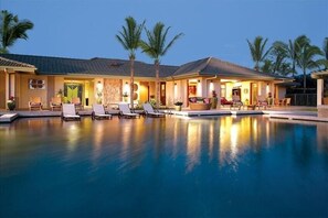 Un resort con piscina, sillas de descanso y palmeras.