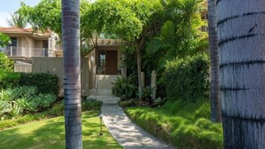 A pathway leading to a house surrounded by lush greenery and palm trees. - 129B Hualalai (Kailua-Kona)