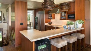 A modern kitchen with wooden cabinets, stainless steel appliances, and a central island with stools. - 129B Hualalai (Kailua-Kona)