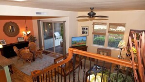 A dining area with a wooden table and chairs, a kitchen with a stove, and a television. - Fairways at Mauna Lani 1104 (Kamuela)