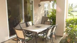 Eine Terrasse mit Tisch, Stühlen, einer Glasschiebetür und einem Blumentopf.